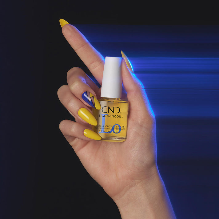 Hand holding a bottle of CND Lightning Oil with a dark background