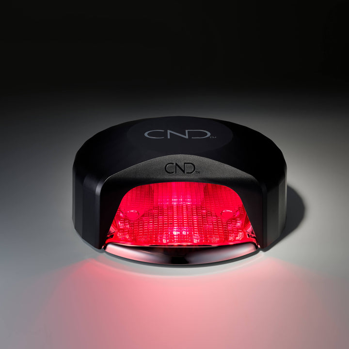 Black nail lamp with red light on a dark background