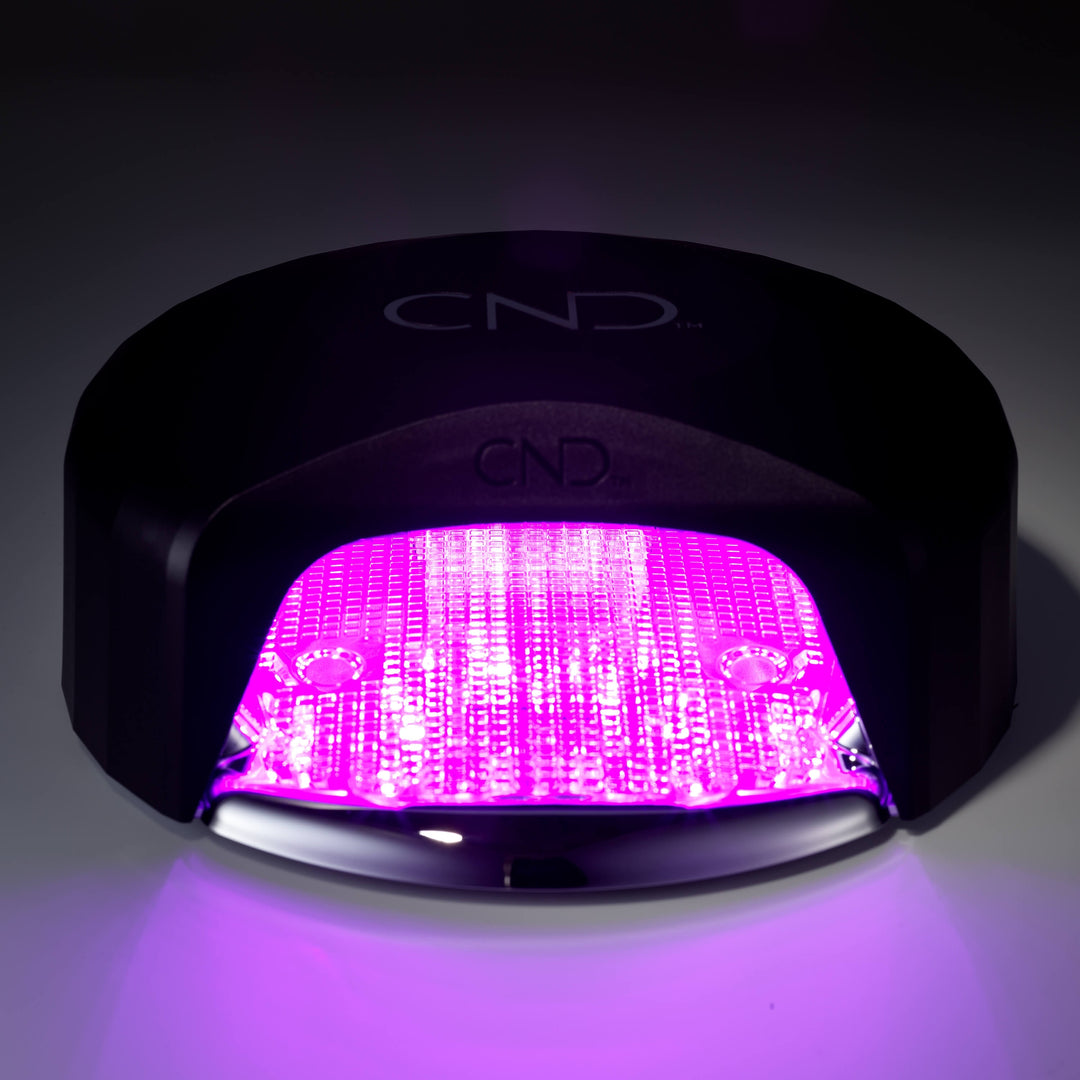 CND visible light lamp with pink light on a dark background