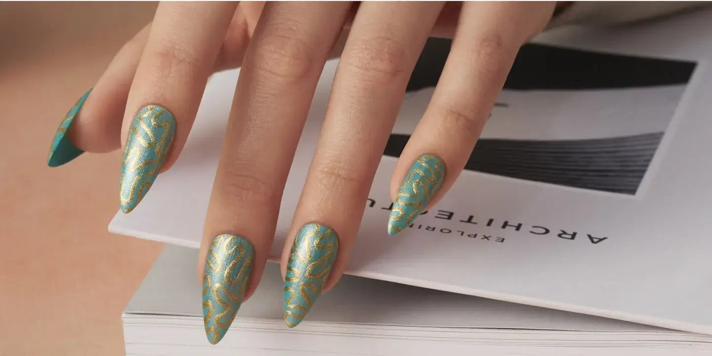 Close-up of a hand with green and gold patterned CND nail polish holding an architectural magazine